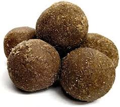 Bellam Minapa Sunnundalu made with urad dal, jaggery, and ghee on a traditional plate