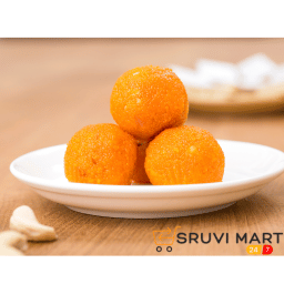 Fresh homemade boondi laddu made with ghee and sugar syrup on a decorative plate.
